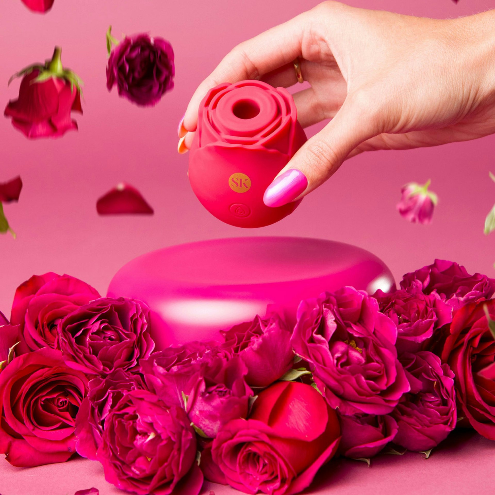 A woman's hand reaching for a pink vase with roses on it